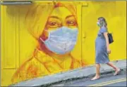  ?? AFP ?? THE WRITING IS ON THE WALL: A woman wearing a face mask walks past a graffiti in Hong Kong.