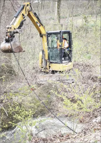  ?? Brodie Johnson • Times-Herald ?? The Forrest City Fire Department partnered with the public works department today to clear a drain culvert in the Edgewood subdivisio­n. Marvin Washington, a FCPWD employee, breaks the tire used to clear the culvert loose as water begins to pour from the culvert.