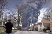  ?? AP photo ?? A man takes photos as a black plume rises over East Palestine, Ohio, as a result of a controlled detonation of a portion of the derailed Norfolk Southern trains on Monday.