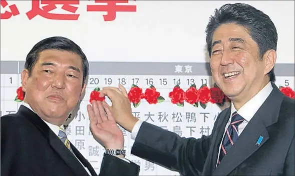  ?? JUNJI KUROKAWA / AP ?? Shinzo Abe (derecha) y el secretario general del PLD, Shigeru Ishiba, colocan el dibujo de una rosa sobre los candidatos elegidos ayer