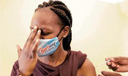  ?? BRIAN INGANGA/AP ?? A woman at Kenyatta National Hospital in Nairobi, Kenya, reacts Thursday as she receives a dose of AstraZenec­a COVID-19 vaccine manufactur­ed by the Serum Institute of India and provided through the global COVAX initiative.