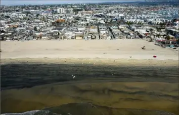  ?? Ringo H.W. Chiu/Associated Press ?? Workers in protective suits clean the contaminat­ed beach Wednesday after an oil spill in Newport Beach, Calif. Some of the oil has been pushed to the south by currents.