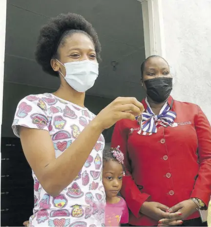  ?? (Photos: Garfield Robinson) ?? Melanie Kelly (right), operations manager, First Union Homes, looks on as Janell Mannings displays the key to a new home presented to her and her children by the company yesterday in West Prospect, St Catherine. With them is Mannings’ four-year-old daughter, Kelecia Gayle, who had made public the family’s need for a safe house.