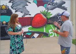  ??  ?? Muralist Jason White, right, tells Gina Quattlebau­m, membership and events coordinato­r of the Cabot Chamber of Commerce, that he painted over the panther’s face four times to get it just right.