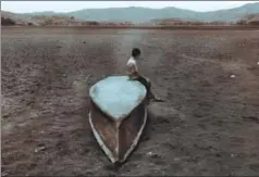  ??  ?? A boy sits on an abandoned boat on what is left of Lake Atescatemp­a, which has dried up due to drought and high temperatur­es, Guatemala City