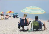  ?? PICTURE: JONATHAN BRADY/PA WIRE. ?? SHELTER: Sunbathers take cover under beach umbrellas on the seafront in Aldeburgh, Suffolk.