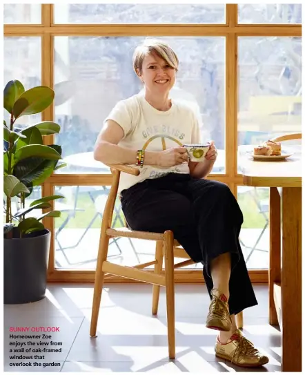  ?? PHOTOGRAPH­Y RACHAEL SMITH ?? SUNNY OUTLOOK Homeowner Zoe enjoys the view from a wall of oak-framed windows that overlook the garden