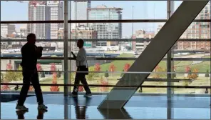  ?? Arkansas Democrat-Gazette/BENJAMIN KRAIN ?? Visitors to the Clinton Presidenti­al Center walk past a window that overlooks Little Rock’s downtown skyline. Pulaski and Garland counties led the state in generating tourist dollars in 2015, according to a report last week from the state Department of Parks and Tourism.