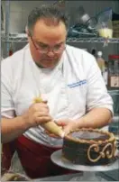  ?? PHOTO BY EMILY RYAN ?? Chef Jean-Pierre Bournazel decorates a praline chocolate cake.