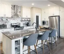  ??  ?? The central L-shaped kitchen has a stylish and colourful full-height backsplash as its eye-catching focal point.