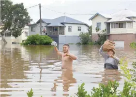  ?? — Reuters ?? Residents wade through floodwater­s near their homes in the northern New South Wales town of Lismore on Friday.