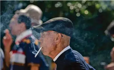  ??  ?? A man smokes in a designated smoking zone in Tokyo.