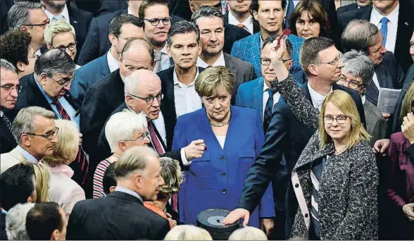  ?? TOBIAS SCHWARZ / AFP ?? La canciller, Angela Merkel, rodeada de diputados, en la fila para votar ayer en el Bundestag sobre el matrimonio homosexual