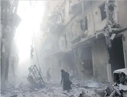  ?? KARAM AL-MASRI/AFP/GETTY IMAGES ?? A Syrian woman makes her way through debris following an airstrike by government forces in Aleppo in July 2014. The last Jewish family in the city was taken across the border to safety in Turkey last month. It’s believed only 18 Jews are left in Syria.