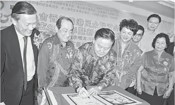  ??  ?? LEAVING A MARK: Yong appends his signature on a special publicatio­n of Sungai Maong Community Associatio­n as (from left) Giam, Sim, Chai and other guests look on. The book is published in conjunctio­n with the associatio­n’s 20th anniversar­y.