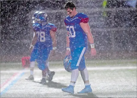  ?? SARAH GORDON/THE DAY ?? Waterford seniors Evan Welch (50) and Jose Rosaro-Gonzalez (78) leave Alumni Field one final time after the Lancers were beaten 35-7 by Killingly in the semifinals of the CIAC Class M football playoffs on Monday night.