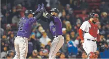  ?? Christophe­r Evans, Boston Herald ?? The Rockies’ Chris Iannetta congratula­tes Charlie Blackmon in front of Red Sox catcher Sandy Leon after Blackmon hit a two-run homer during the eighth inning Tuesday night at Fenway Park.