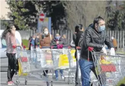  ?? EFE / SERGIO PONTORIERI ?? Cola de compradore­s con mascarilla­s en Italia.