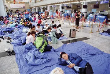  ??  ?? Stranded passengers rest at the departure hall of Jiuzhaigou airport near the remote, mountainou­s area struck by a deadly earthquake in Sichuan province, China. — Reuters photo