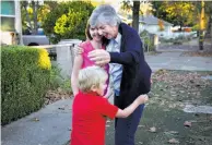  ??  ?? Donna Hickman embraces her grandchild­ren, Alex, 6, and Victoria, 12, during the move to their new home.