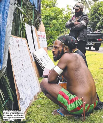  ?? Picture: AFP ?? Voters in Papua look at lists of candidates in Indonesia's presidenti­al and legislativ­e elections.