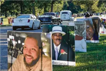  ?? Photos by Carlos Osorio / Associated Press ?? Vehicles drive past photos of Detroit’s victims of COVID-19 at Belle Isle Park in the Michigan city Monday. More than 900 photos submitted by families were turned into large posters and staked around the park.