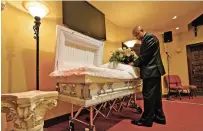  ?? CHRIS O’MEARA/ASSOCIATED PRESS ?? Wayne Bright, funeral director at Wilson Funeral Home, places flowers on a casket before a service Thursday in Tampa, Fla. Bright has seen grief piled upon grief as Florida is in the grip of the deadliest wave since the coronaviru­s pandemic began.