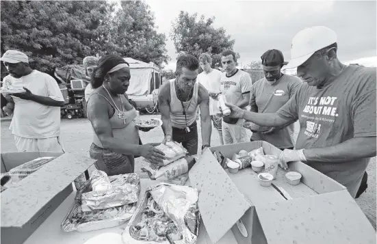  ?? AL DIAZ adiaz@miamiheral­d.com ?? United We All Can Community Services Pastor Frank Diaz, right, delivers food to homeless sex offenders at an encampment at 3600 NW 48th St. in June.