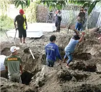  ?? BOY SLAMET/JAWA POS ?? DUA LIANG LAHAD: Anton Ferdianton­o bersama istri, Sari Puspitarin­i, dan putri pertama mereka, Hilya Aulia Rahman, dikubur di makam khusus jenazah tanpa identitas di Jalan Mayjen Sungkono, Sidoarjo, kemarin (18/5).