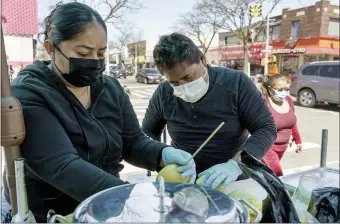  ?? THE ASSOCIATED PRESS ?? Ruth Palacios and Arturo Xelo, a married couple from Mexico, work at their fruit stand in the Corona neighborho­od of the Queens borough of New York. They worked seven days a week for months disinfecti­ng COVID-19patient rooms at the Memorial Sloan Kettering Cancer Center in New York City, but weren’t paid overtime, Palacios says.