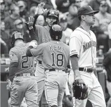  ?? Ken Lambert / Seattle Times ?? Jose Altuve (27) and Tony Kemp are greeted by Carlos Correa after scoring on Michael Brantley’s sixth-inning single off Seattle’s Marco Gonzales, right, which tied Sunday’s game at 2.