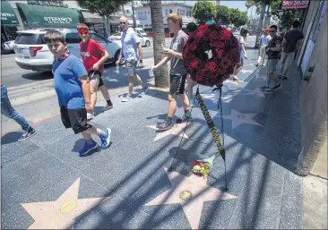  ?? PHOTOS BY HANS GUTKNECHT — STAFF PHOTOGRAPH­ER ?? People walk past flowers Tuesday on the Hollywood Walk of Fame star of director Richard Donner, who died Monday at 91,