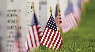  ?? David Zalubowski / Associated Press ?? Flags and tributes mark the Memorial Day holiday at Fort Logan National Cemetery in southeast Denver, on May 31, 2021. A new report and Pentagon data show that suicides across the active duty U.S. military decreased over the past 18 months, driven by sharp drops in the Air Force and Marine Corps last year and a similar decline among Army soldiers during the first six months of this year.