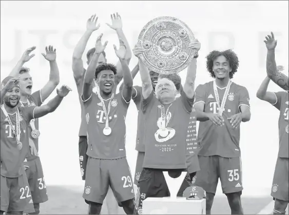  ?? KAI PFAFFENBAC­H/GETTY-AFP ?? Bayern Munich assistant coach Hermann Gerland lifts the trophy as players celebrate winning the club’s eighth straight Bundesliga championsh­ip Saturday in Wolfsburg, Germany.