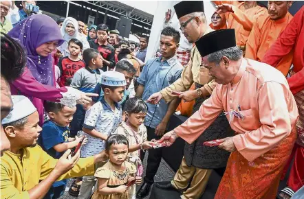  ??  ?? Festive cheer: Mohamad (right) handing out ‘duit raya’ to children at the Majlis Mesra Aidilfitri at the Rural Transforma­tion Centre in Tunjong, Kota Baru. — Bernama