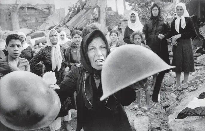  ?? BILL FOLEY / THE ASSOCIATED PRESS ?? A Palestinia­n woman brandishes helmets during a memorial service in Beirut in September of 1982 for victims of Lebanon’s Sabra refugee camp massacre. She claimed the helmets ere worn by those who massacred hundreds of her countrymen. The Only Café Linden MacIntyre Random House Canada 432 pp; $34