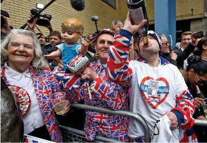  ??  ?? We’ll drink to that! Royal fans toast the newborn prince outside the hospital yesterday