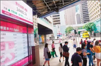  ?? (AP) ?? People wearing a face mask walks past a bank’s electronic board showing the Hong Kong share index at Hong Kong Stock Exchange Tuesday, June 30, 2020. Asian shares are rising, cheered by a rally on Wall Street that underlined
some optimism about global business performanc­e despite the ongoing coronaviru­s pandemic.