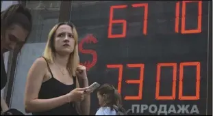  ?? ASSOCIATED PRESS ?? A woman walks past an exchange office screen showing the currency exchange rates of US Dollar to Russian Rubles, July 5, in St. Petersburg.