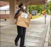  ??  ?? Twin Rivers Middle School Resource Officer Trakida Maldonado helps as parents and students pick up and drop off items recently at the campus in Buford.