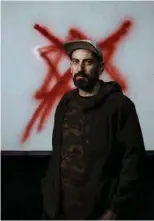  ?? — AFP photos ?? Ahmad Tobasi, artistic director of the Freedom Theatre, poses for a picture in front of a red X spray painted over a Star of David left by Zionist soldiers during a recent raid, on the screen of the cinema in the Jenin refugee Camp on Dec 23, 2023.