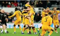  ?? Photo: AFP ?? Cambridge United players and staff celebrate their historic FA Cup victory against Newcastle United at St. James’ Park last Saturday (Jan 8).