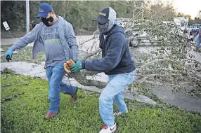  ?? SANDY HUFFAKER/ GETTY IMAGES ?? Workers clear debris from Hurricane Zeta at a school Oct. 29 in St. Bernard, La. The Gulf Coast endured prolonged destructio­n.