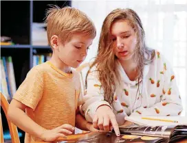  ?? [PHOTO BY DOUG HOKE, THE OKLAHOMAN] ?? Denae Chanlder, 15, helps her brother, Zak, 6, with his work on Friday.