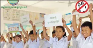  ?? ENVIRONMEN­T MINISTRY ?? Students hold signs pledging to stop using plastic at an elementary school in Prey Veng province in November.