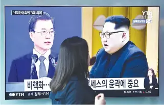  ?? AFP ?? A WOMAN walks past a news screen showing file footage of South Korean President Moon Jae-in and North Korean leader Kim Jong Un at a railway station in Seoul in this April 25 photo. North Korean leader Kim Jong Un will walk across the Demilitari­zed...