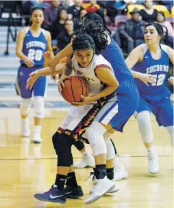  ?? LUIS SÁNCHEZ SATURNO/THE NEW MEXICAN ?? Santa Fe Indian School’s Leanna Lewis, center front, gets a rebound away from Socorro’s Zoe Esquivel during Friday’s game at Santa Fe Indian School.