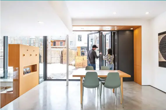  ??  ?? A deep Douglas fir surround in the living room frames the bi-fold front entrance door by Bigfoot. Radiant-heated polished cement floors run throughout.