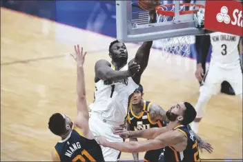  ?? ASSOCIATED PRESS ?? NEW ORLEANS PELICANS FORWARD ZION WILLIAMSON (1) goes to the basket over Utah Jazz forward Georges Niang (left) and center Rudy Gobert (right) in the first half of an NBA game in New Orleans on Monday.