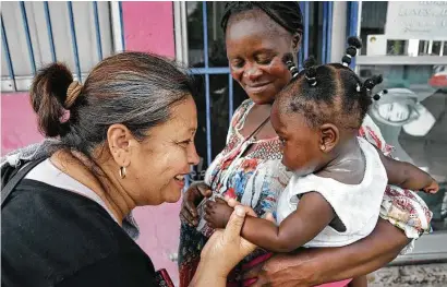  ?? Photos by Bob Owen / Staff photograph­er ?? Eli Martinez of Nuevo Laredo admires a baby held by pregnant mom Ebonze Mputu Bola outside a municipal shelter.